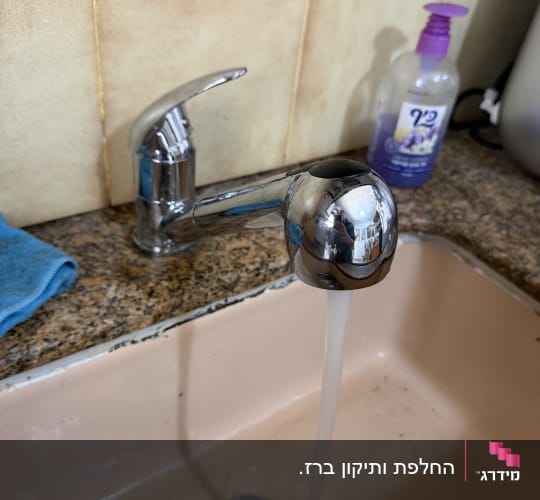 ברז מים זורם בכיור מטבח עם סבון ידיים